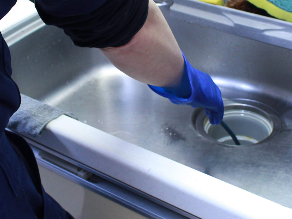 ブレイブロータスのスタッフが台所排水管の高圧洗浄を行なっている写真